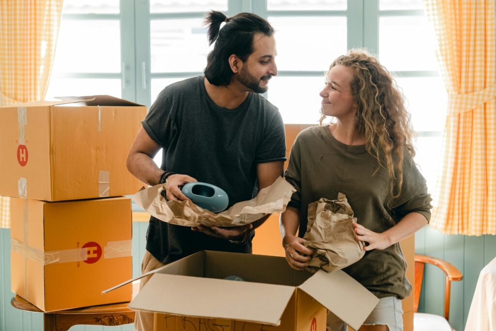 A cheerful couple unpacking boxes in their new apartment, smiling at each other.